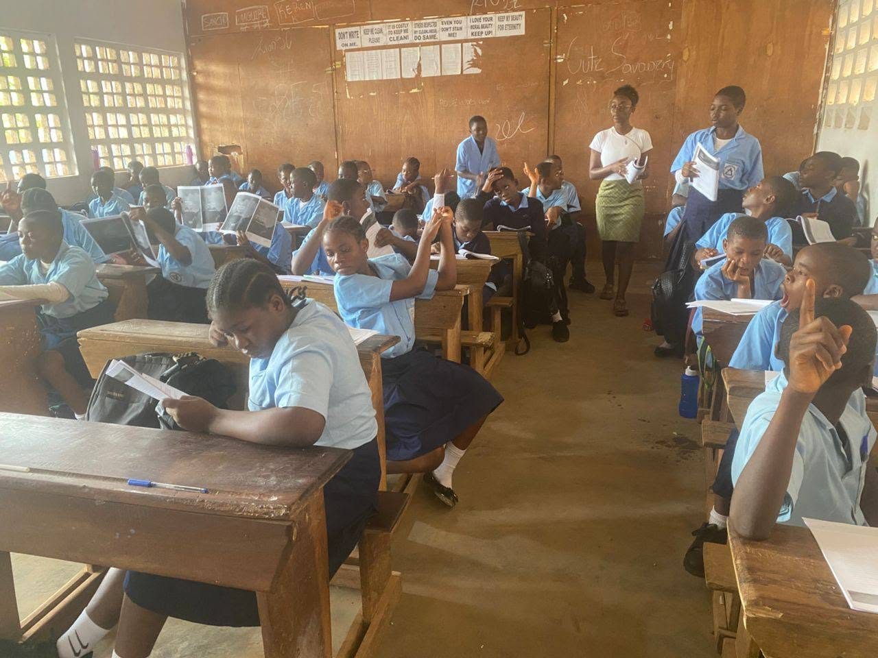Students in blue uniforms reading manuals in classroom