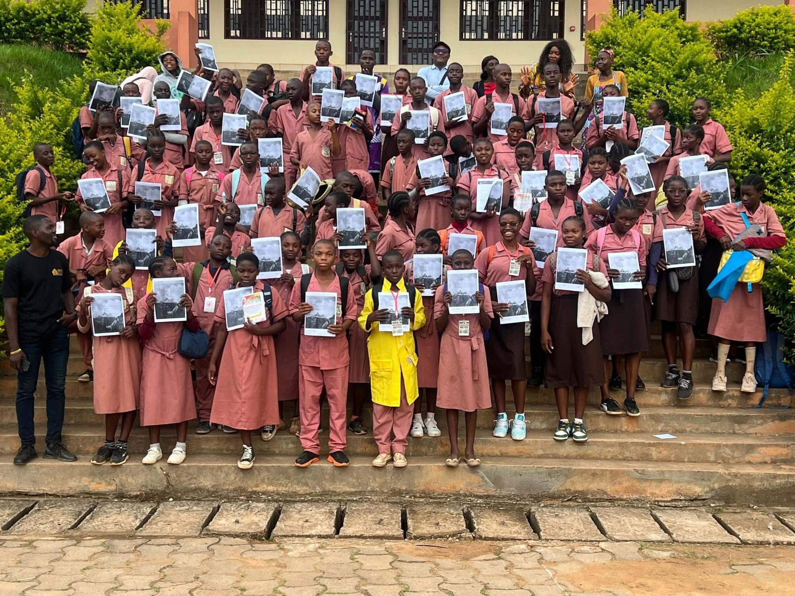 Large student cohort holding leadership manuals on school steps