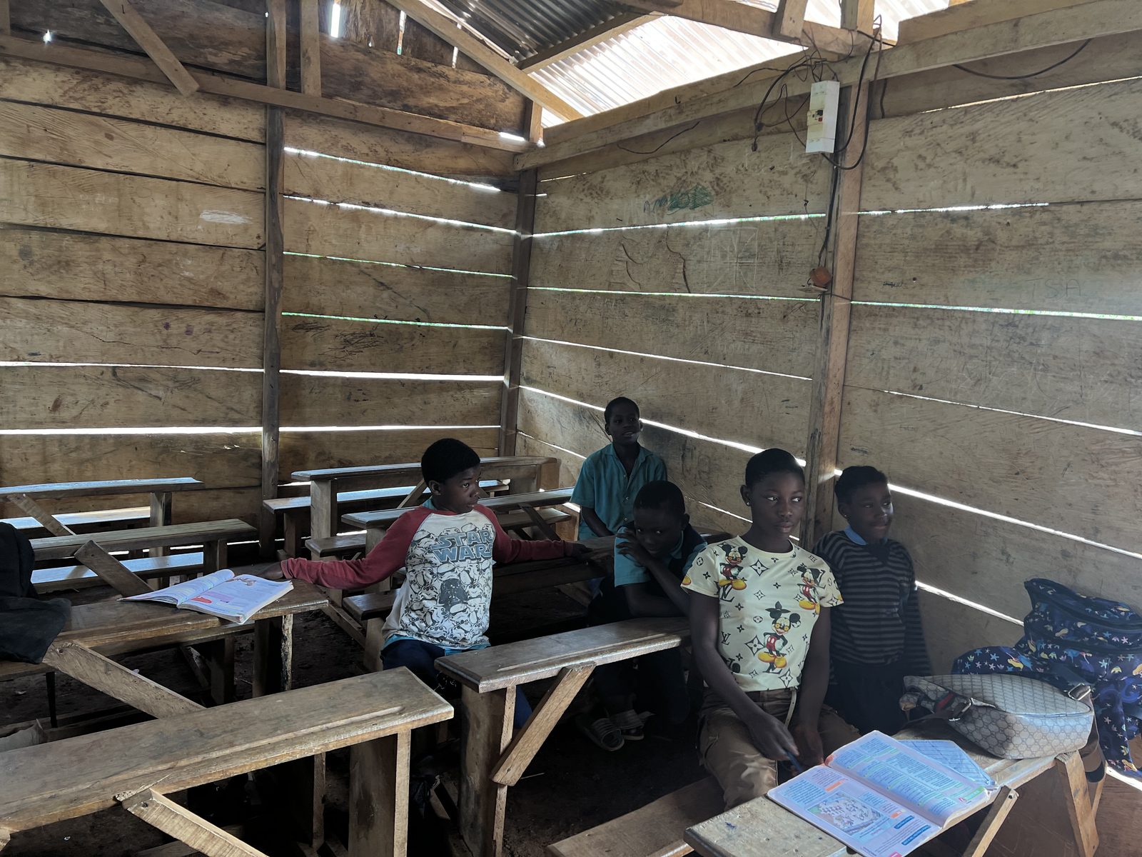 Children seated on bare wooden benches in a rural classroom